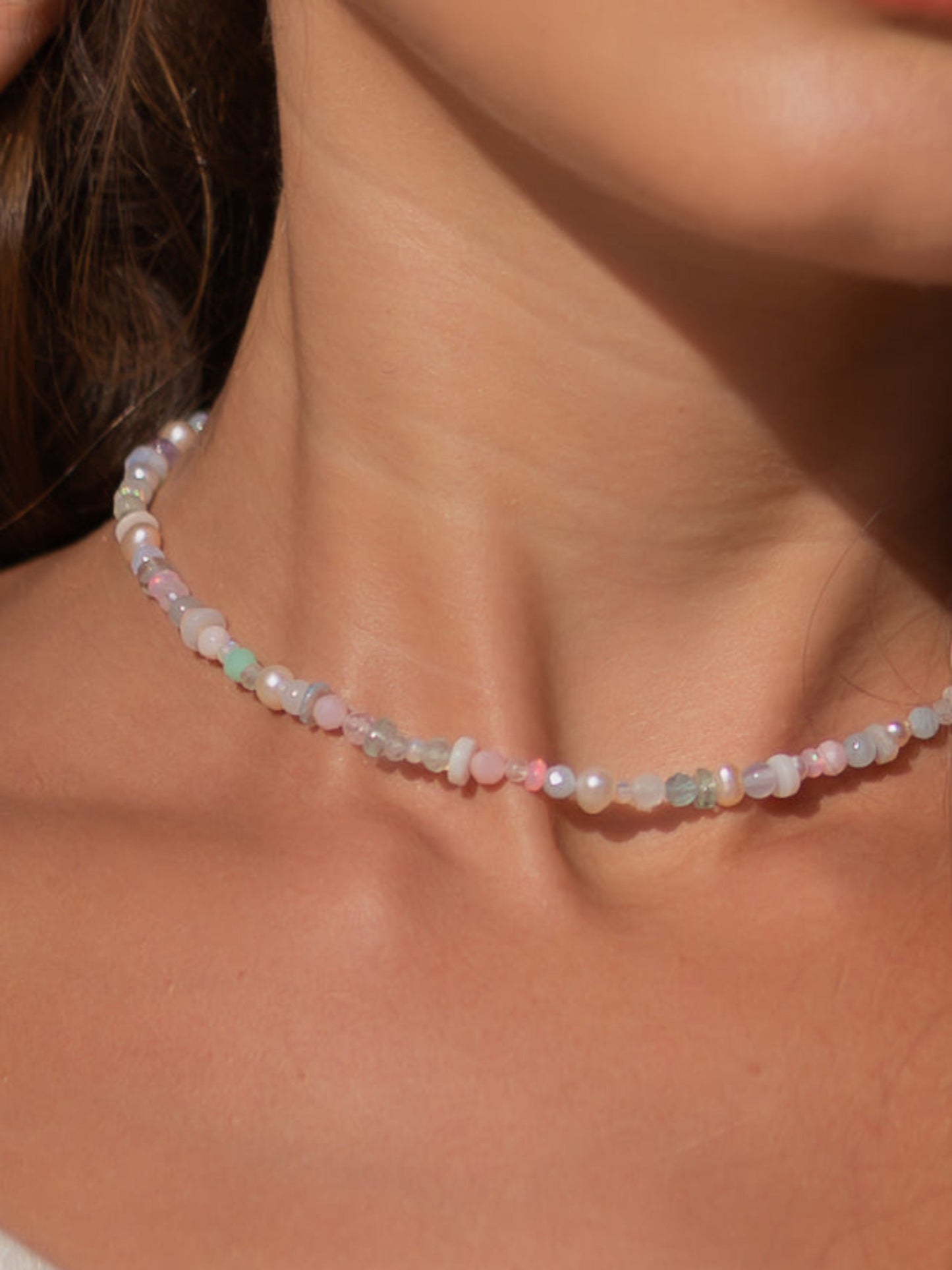 Close-up of a woman wearing a delicate beaded necklace on a blurred background