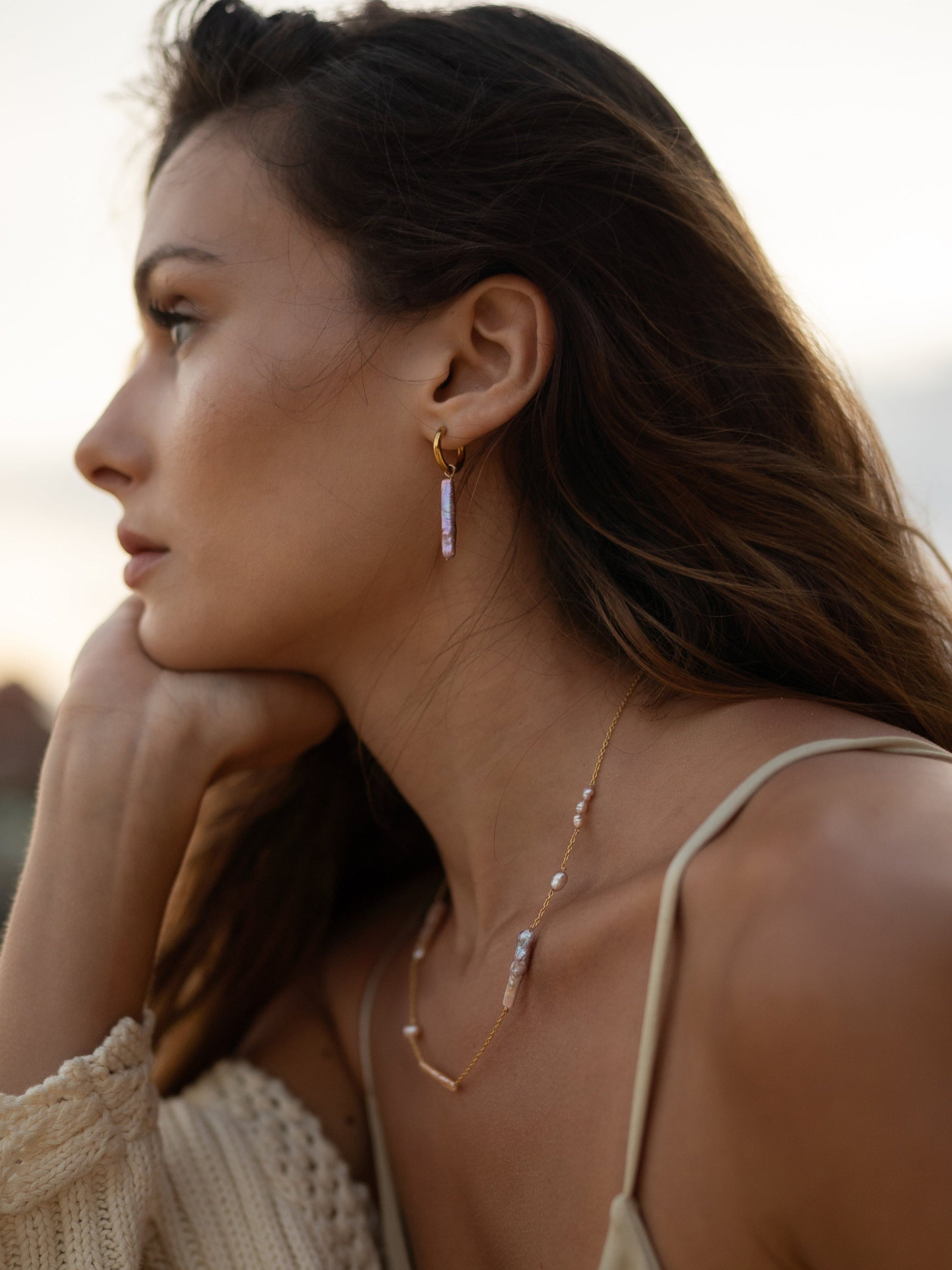 Woman wearing a necklace and earrings with a blurred background