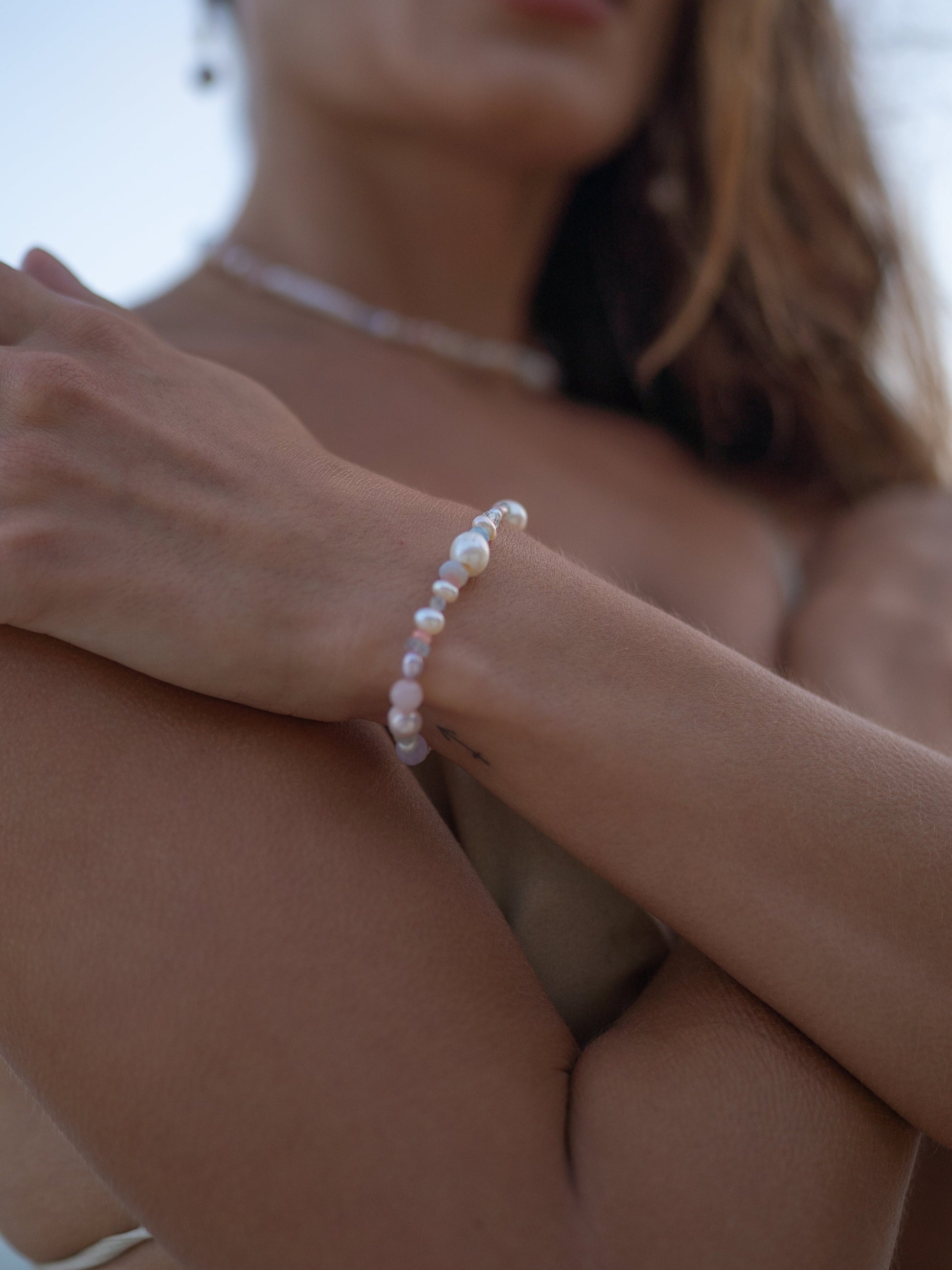 Close-up of a person wearing a pearl bracelet with a blurred background