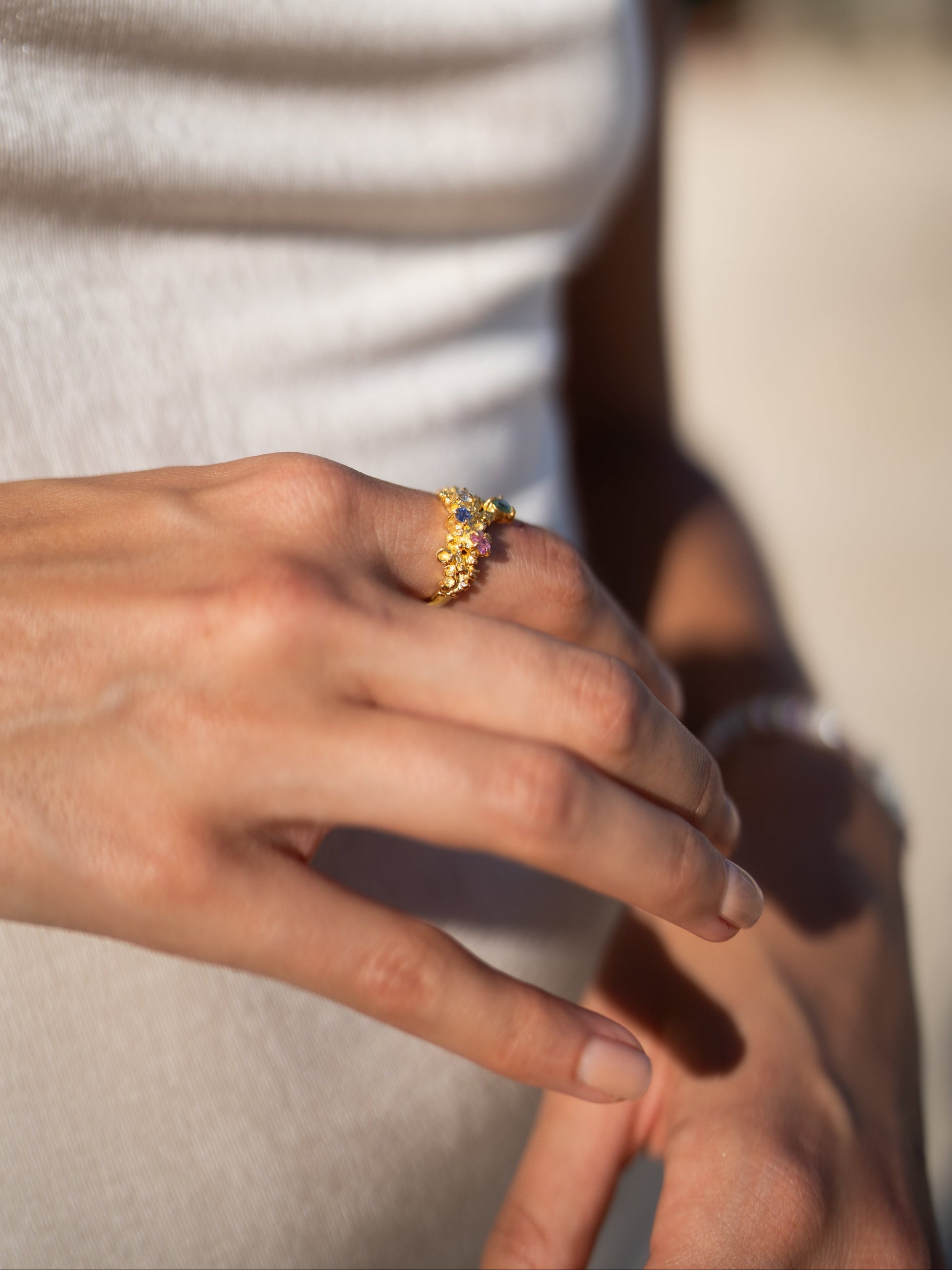 Close-up of a hand wearing a gold ring with a blurred background