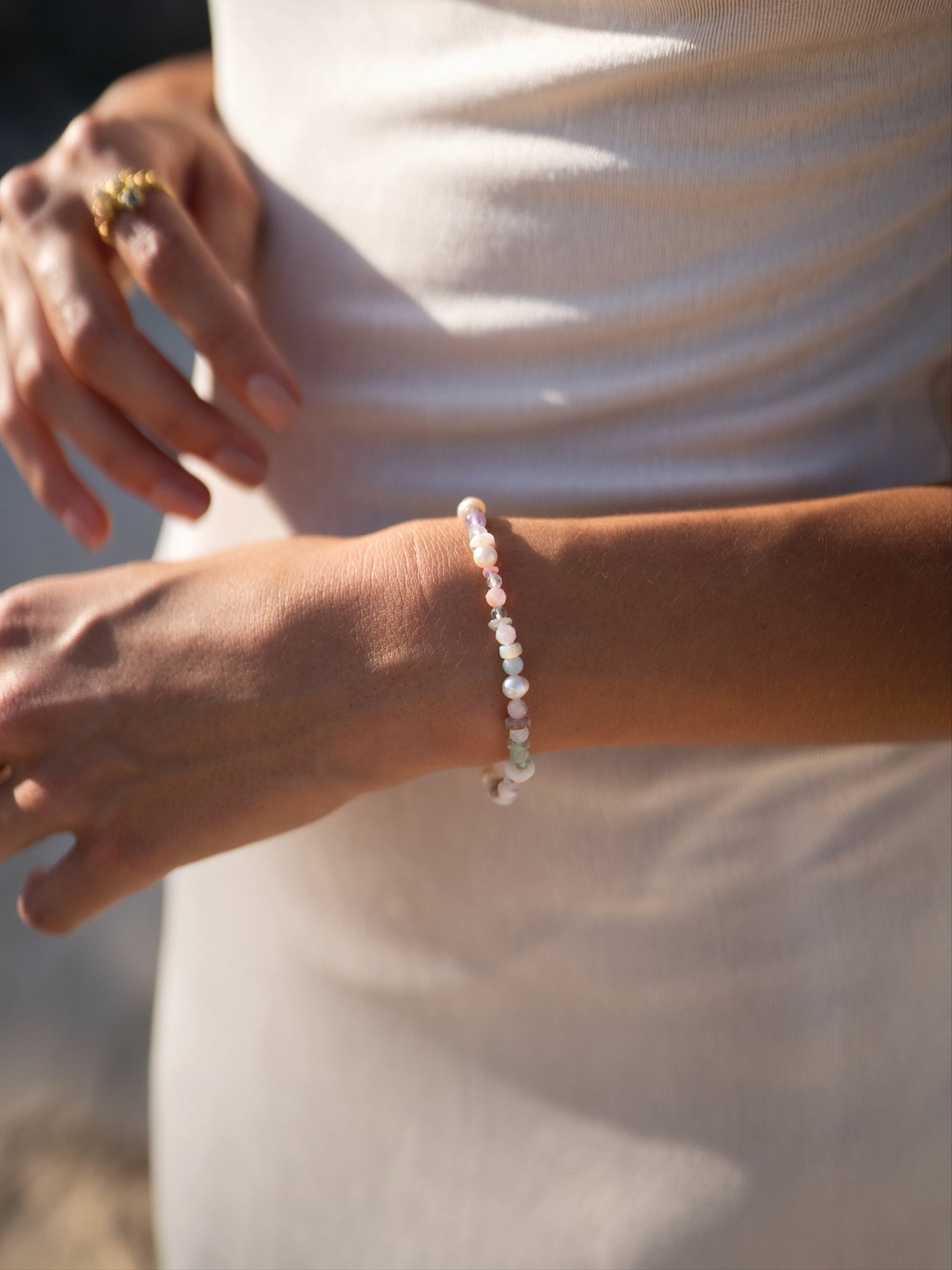 Close-up of a person's wrist wearing a pearl bracelet with a blurred background