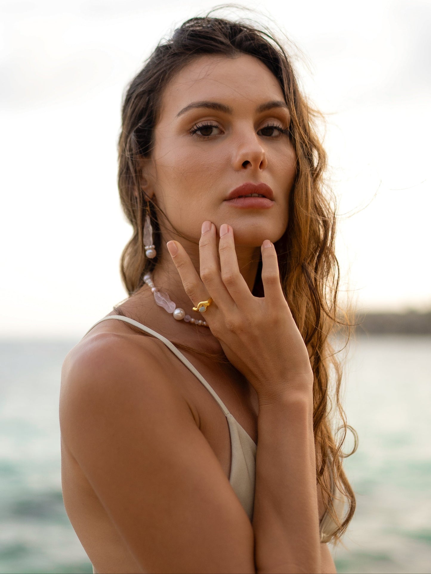 Woman with hand on face against a blurred natural background