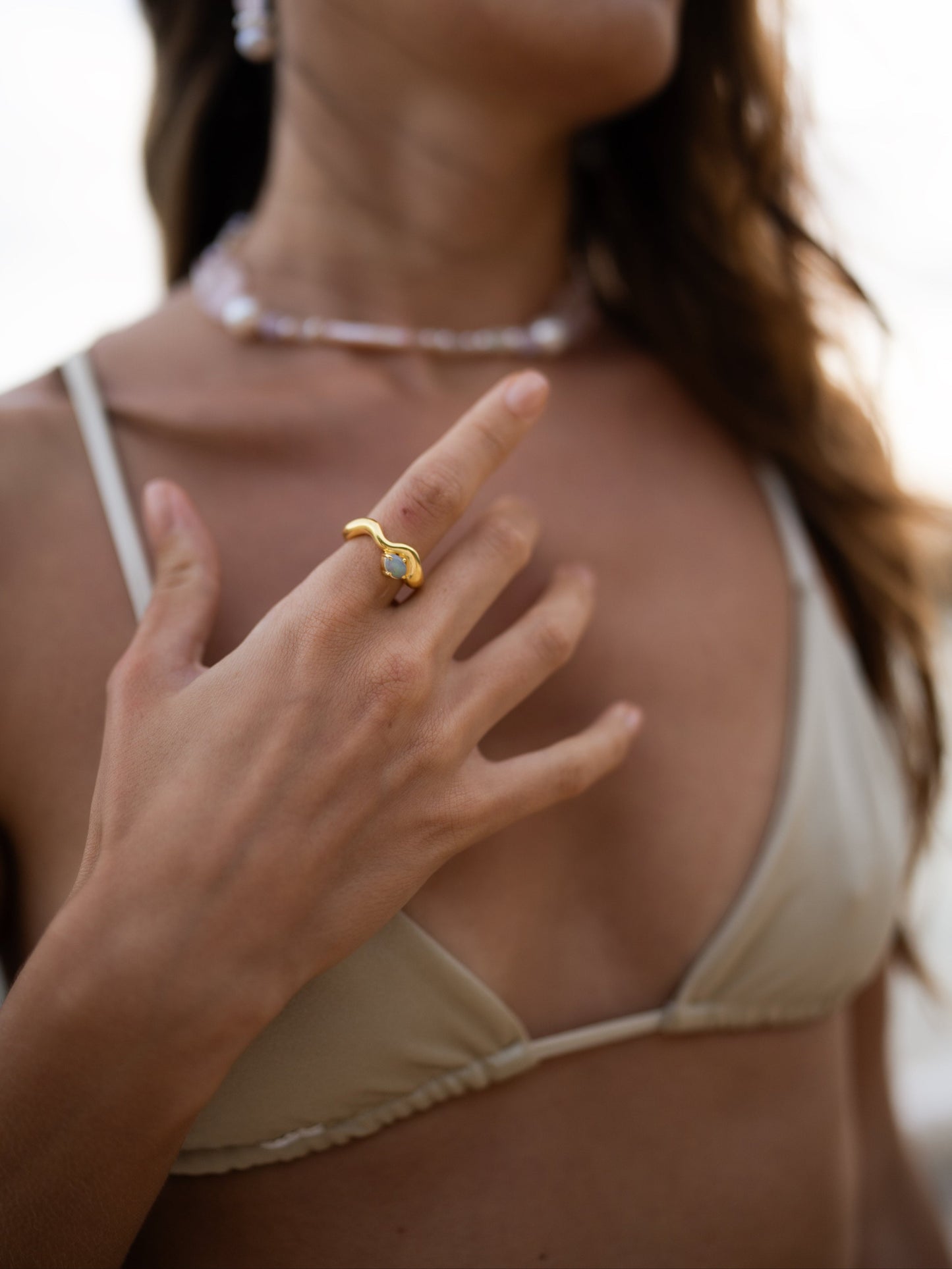 Close-up of a woman wearing a gold ring with a diamond, blurred background