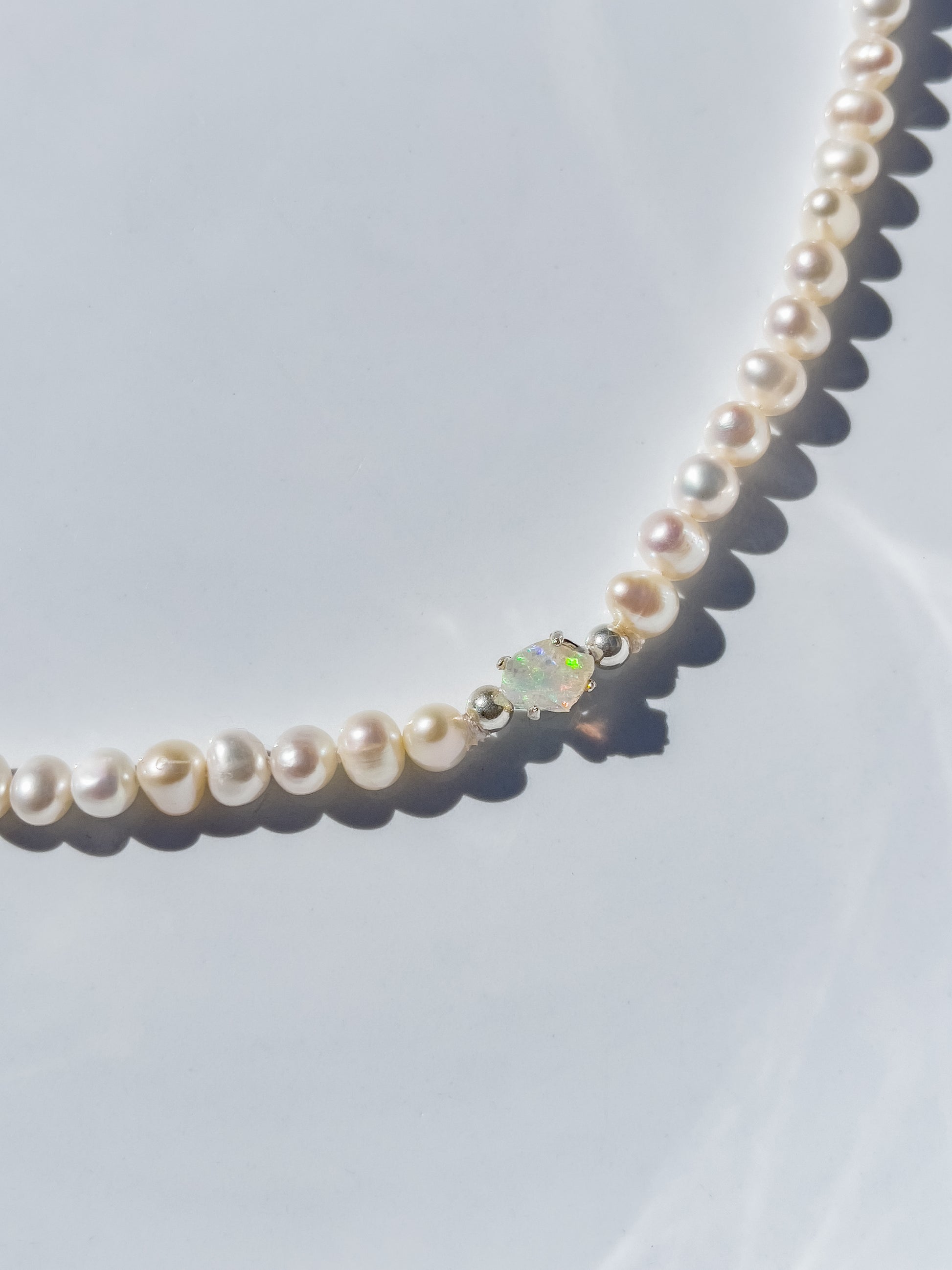 Pearl & Raw Opal Choker Necklace. Natural AA luxe pearls in a natural white are highlighted by the bright iridescent sparkle of Raw Australian Opal placed centrally on the clavicle, held in a sterling silver setting. Personally and strung and knotted with 100% silk thread & handcrafted in Sterling Silver. This necklace is a true statement piece. Please note that this style is made to order, and due to the natural and raw elements, each piece is completely unique.