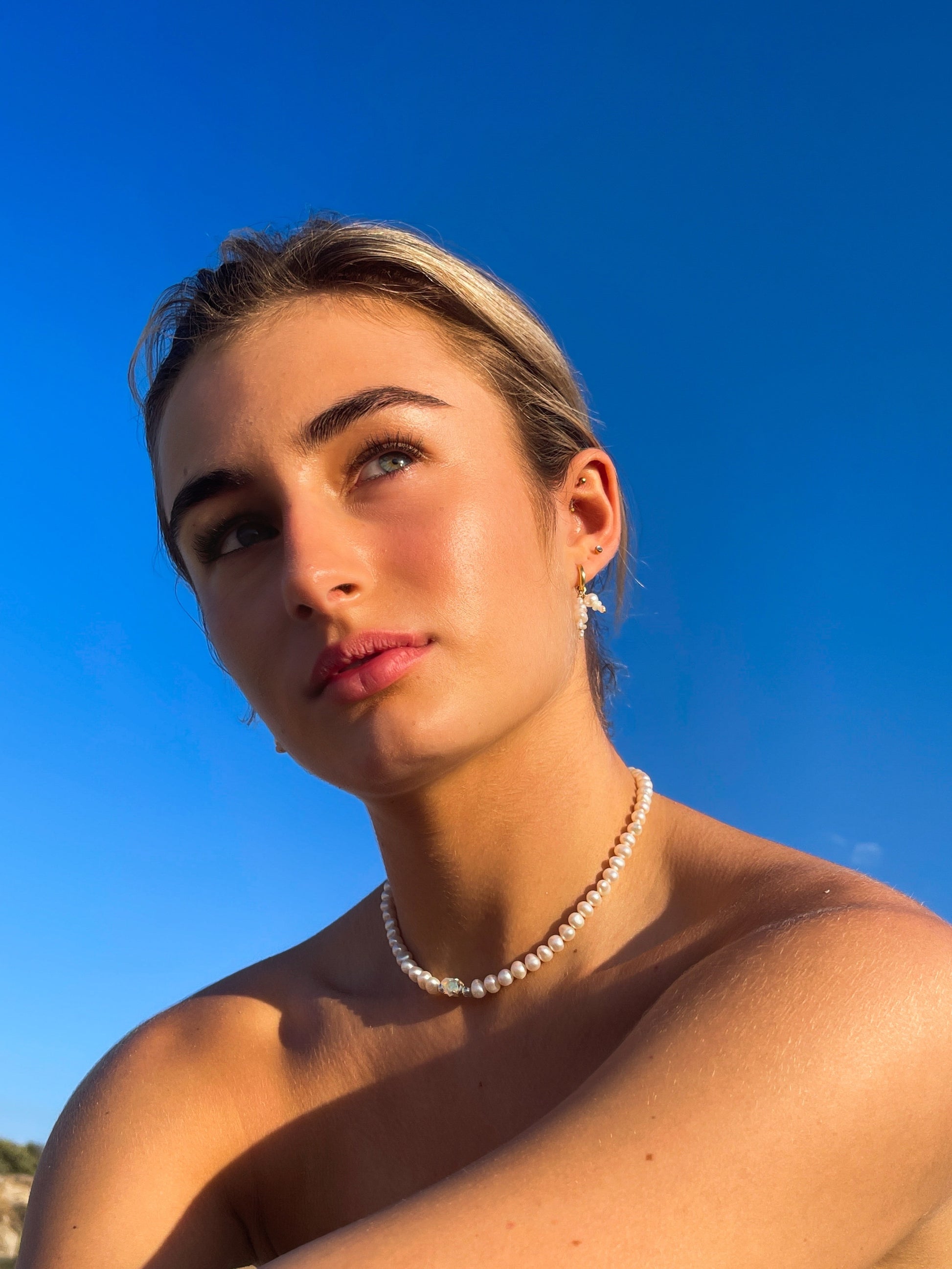 Pearl & Raw Opal Choker Necklace. Natural AA luxe pearls in a natural white are highlighted by the bright iridescent sparkle of Raw Australian Opal placed centrally on the clavicle, held in a sterling silver setting.  Personally and strung and knotted with 100% silk thread & handcrafted in Sterling Silver.   This necklace is a true statement piece.  Please note that this style is made to order, and due to the natural and raw elements, each piece is completely unique.