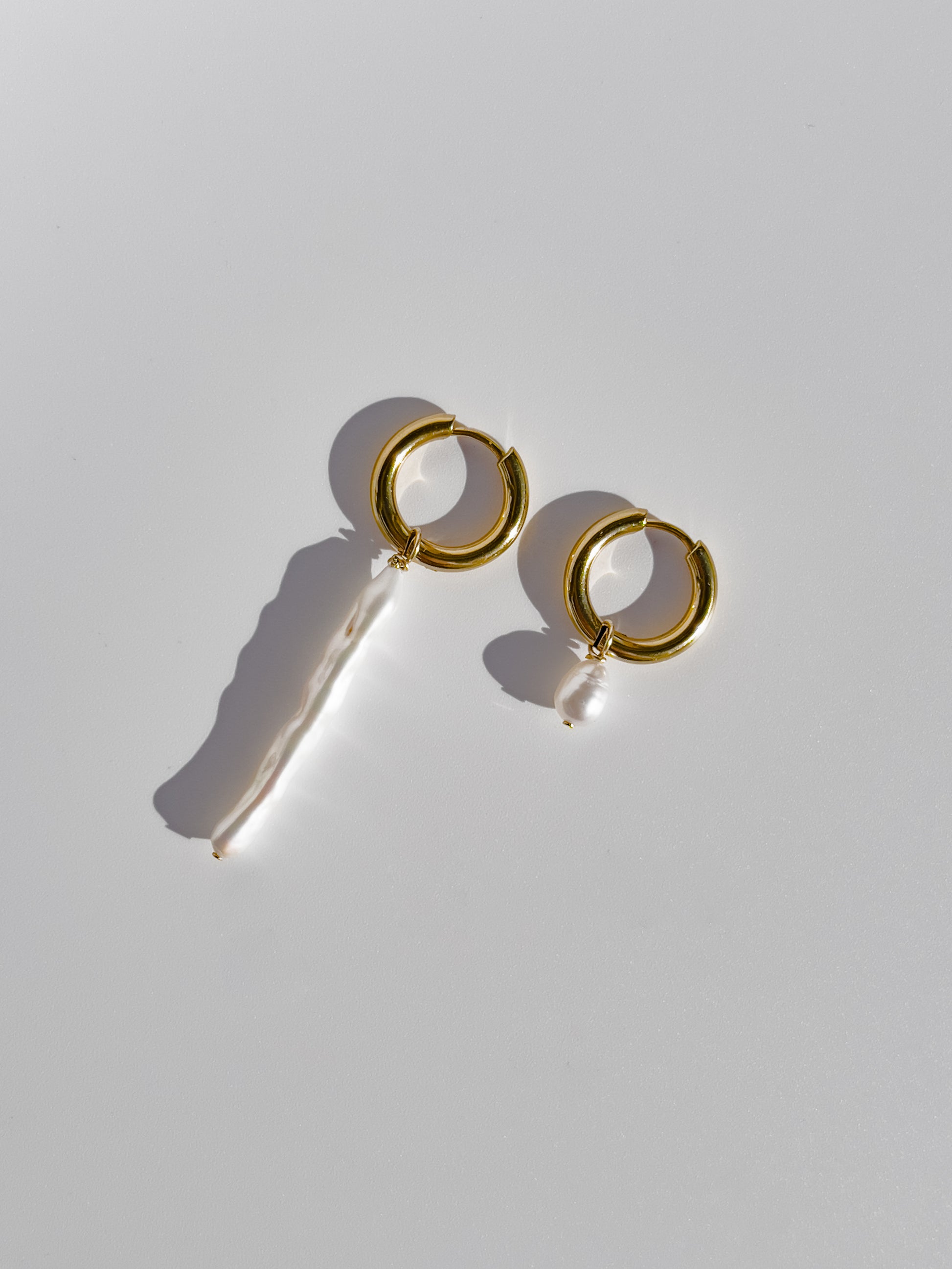 Biwa Pearl Gold Hoops. Chunky 18 karat Gold filled hoops, suspends both elongated Biwa, and round, natural AAA quality freshwater pearls, in a minimal asymmetrical design. Designed and made by nāmaka