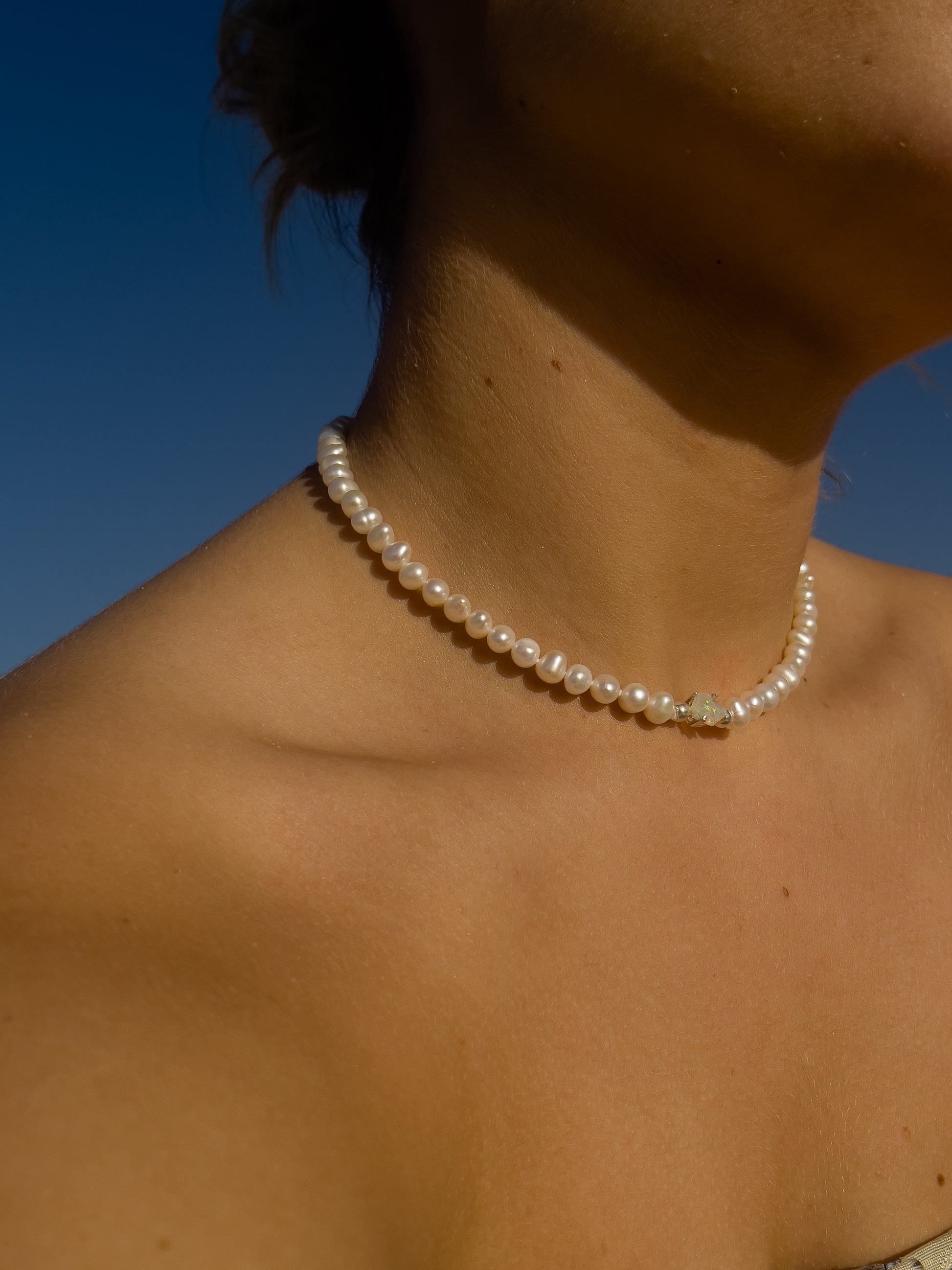Pearl & Raw Opal Choker Necklace. Natural AA luxe pearls in a natural white are highlighted by the bright iridescent sparkle of Raw Australian Opal placed centrally on the clavicle, held in a sterling silver setting.  Personally and strung and knotted with 100% silk thread & handcrafted in Sterling Silver.   This necklace is a true statement piece.  Please note that this style is made to order, and due to the natural and raw elements, each piece is completely unique.