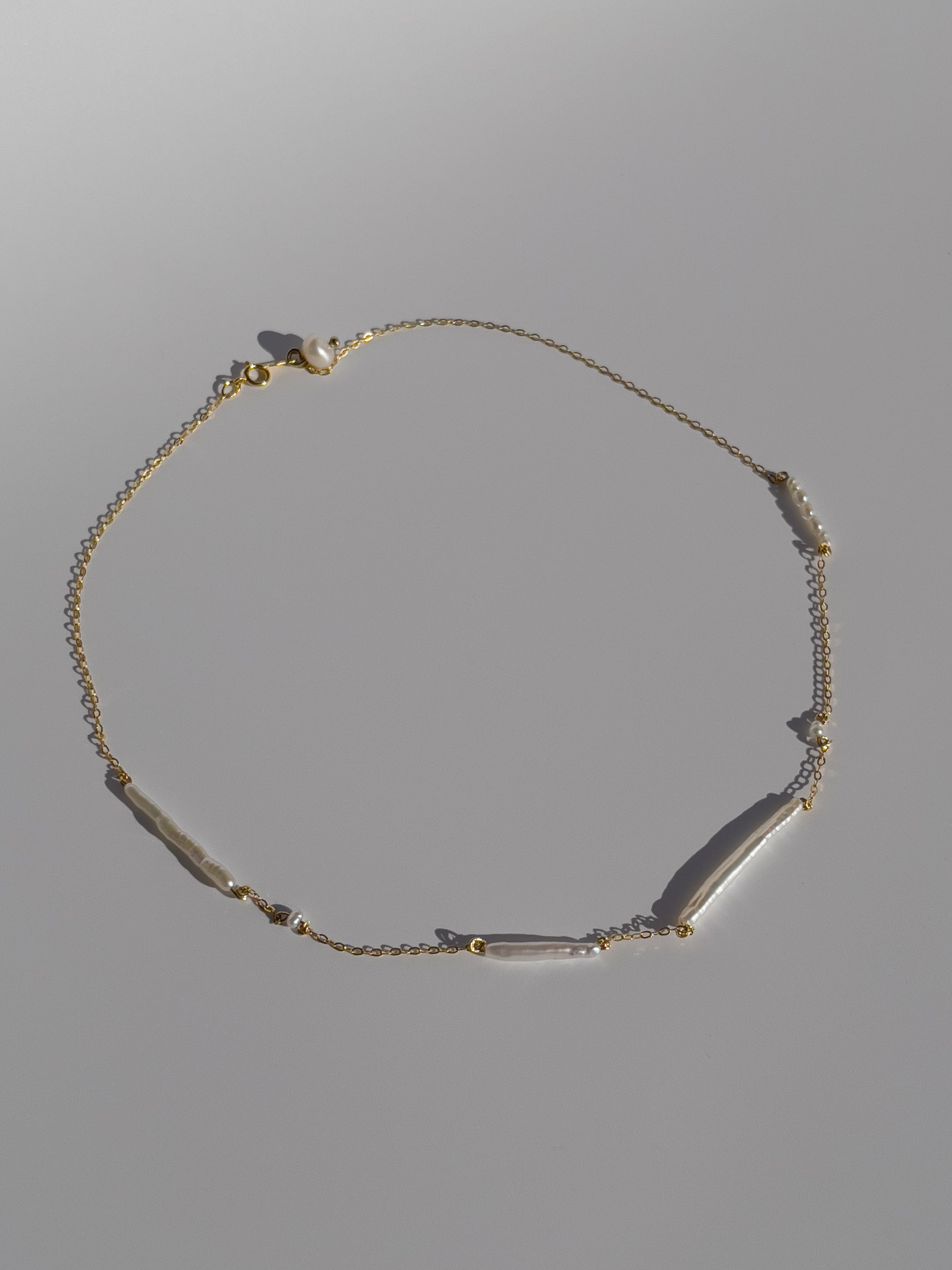 Biwa pearl gold necklace. This ultra fine 14 karat Gold filled with sterling silver flat cable chain suspends gorgeous Biwa elongated freshwater pearls and freshwater seed pearls. Designed and made by nāmaka.