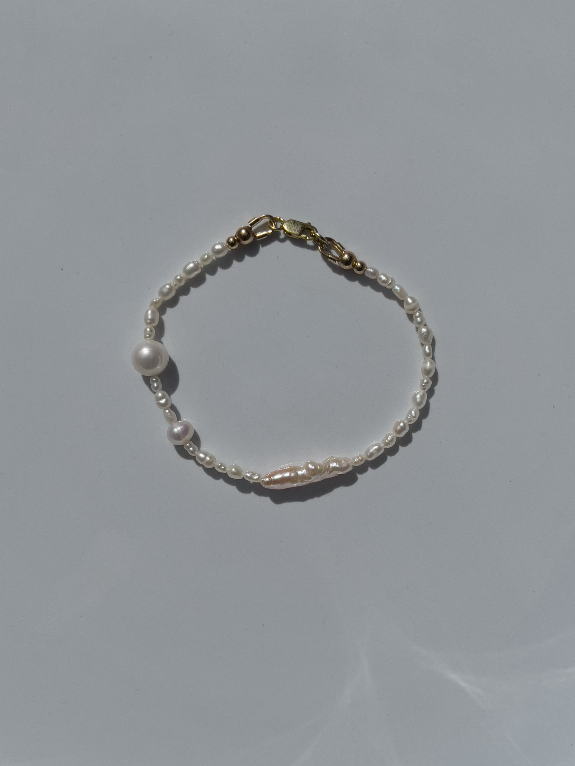 Biwa Pearl Bracelet. Natural elongated Biwa pearls placed off centre with a bold spherical Freshwater pearls. Using natural AAA quality freshwater pearls, in a minimal asymmetrical design. 14 Karat Gold filled Sterling Silver hardware finishes the piece. Designed and made by nāmaka