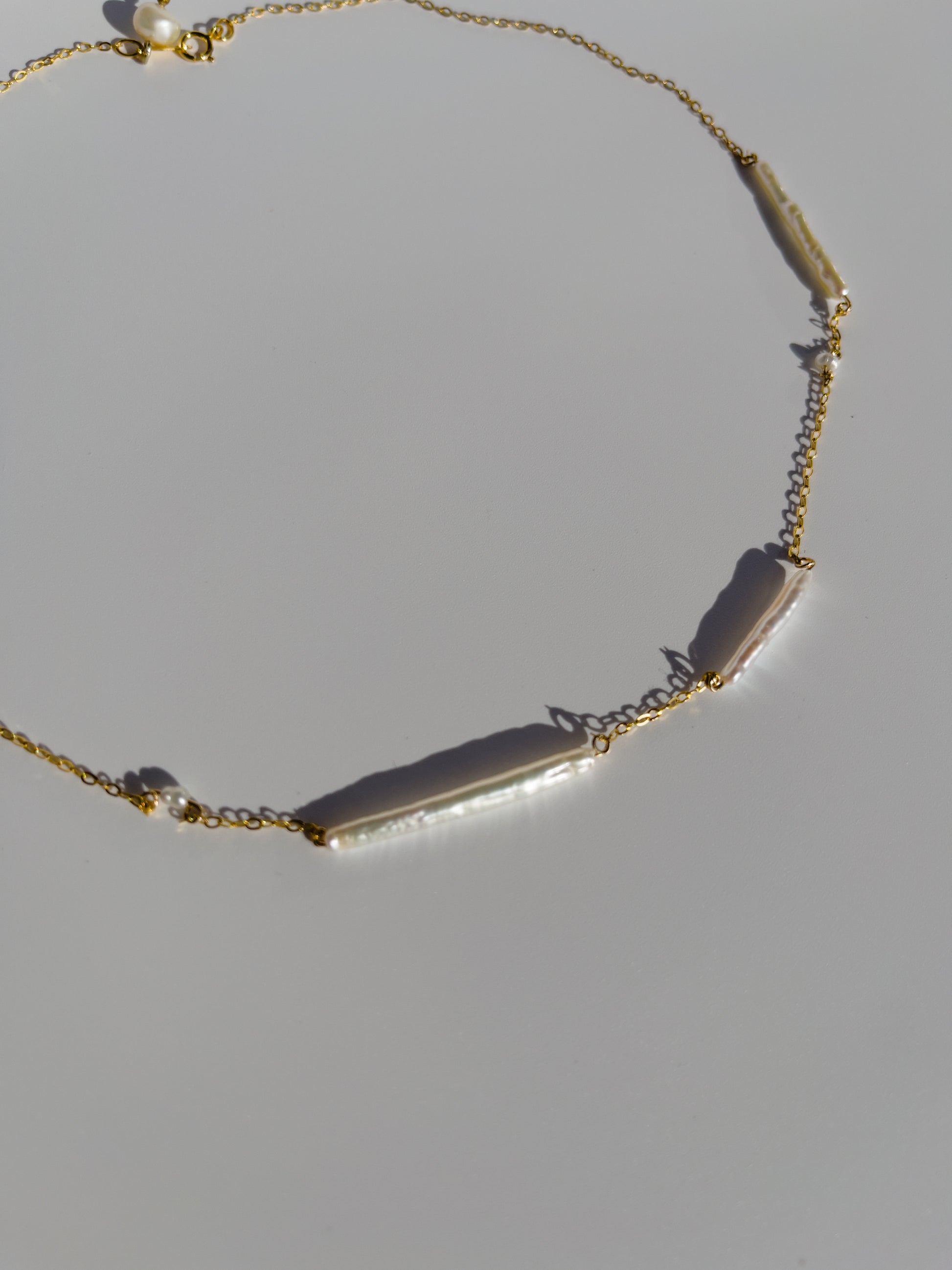 Biwa pearl gold necklace. This ultra fine 14 karat Gold filled with sterling silver flat cable chain suspends gorgeous Biwa elongated freshwater pearls and freshwater seed pearls. Designed and made by nāmaka.