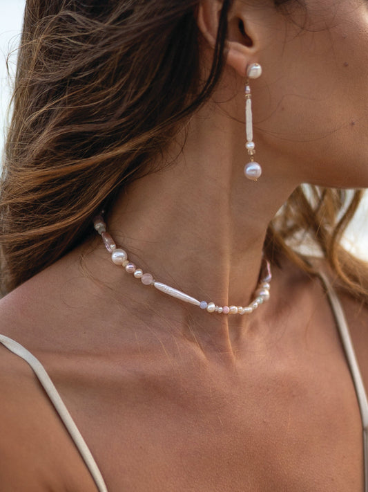 Pearl necklace and earrings on a person with a blurred background
