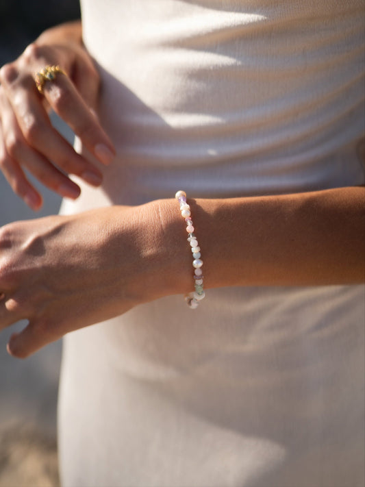 Close-up of a person's wrist wearing a pearl bracelet with a blurred background