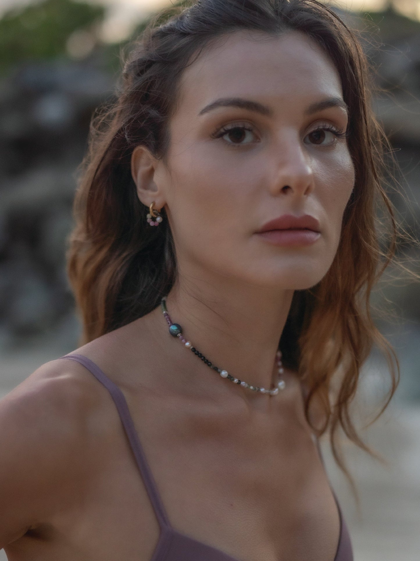 Woman wearing a necklace with a blurred natural background