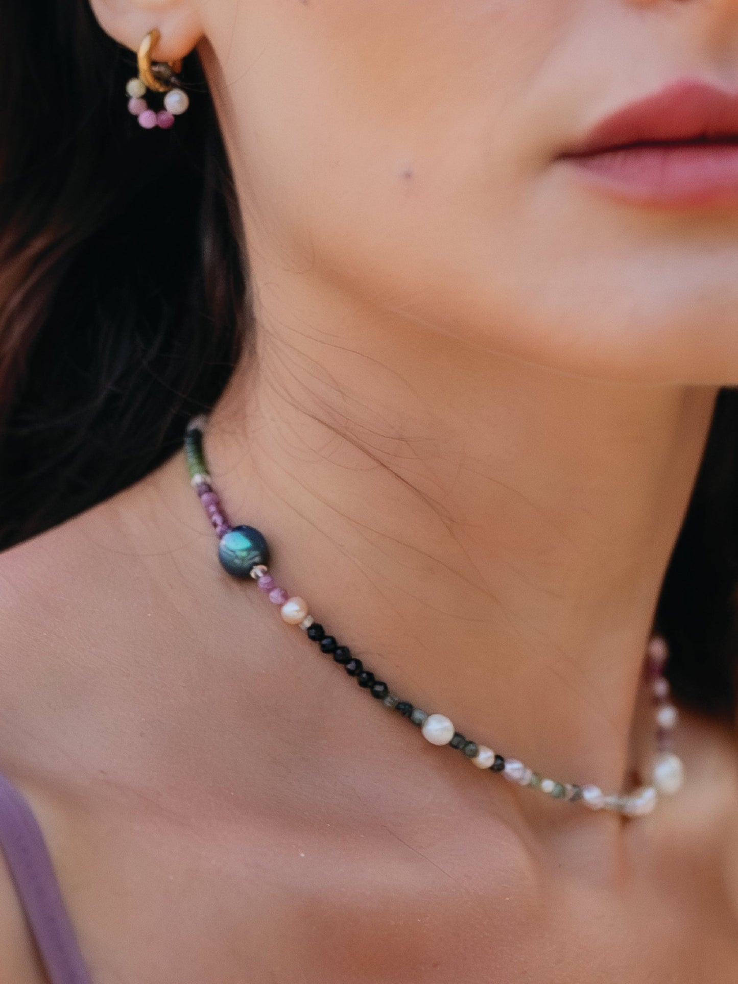 Close-up of a person wearing a beaded necklace and earrings.