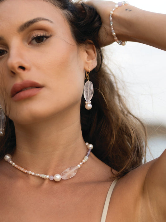 Woman wearing a pearl necklace and earrings with a blurred background