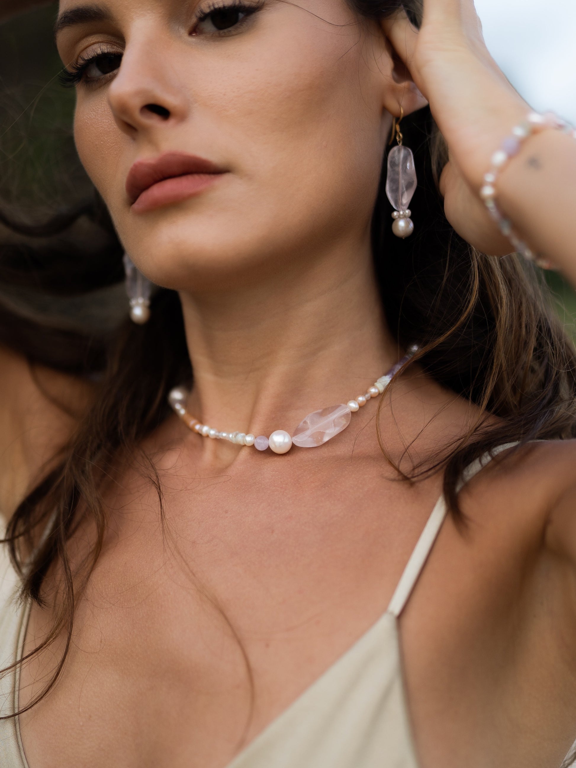 Woman wearing a pearl necklace and earrings with a blurred background