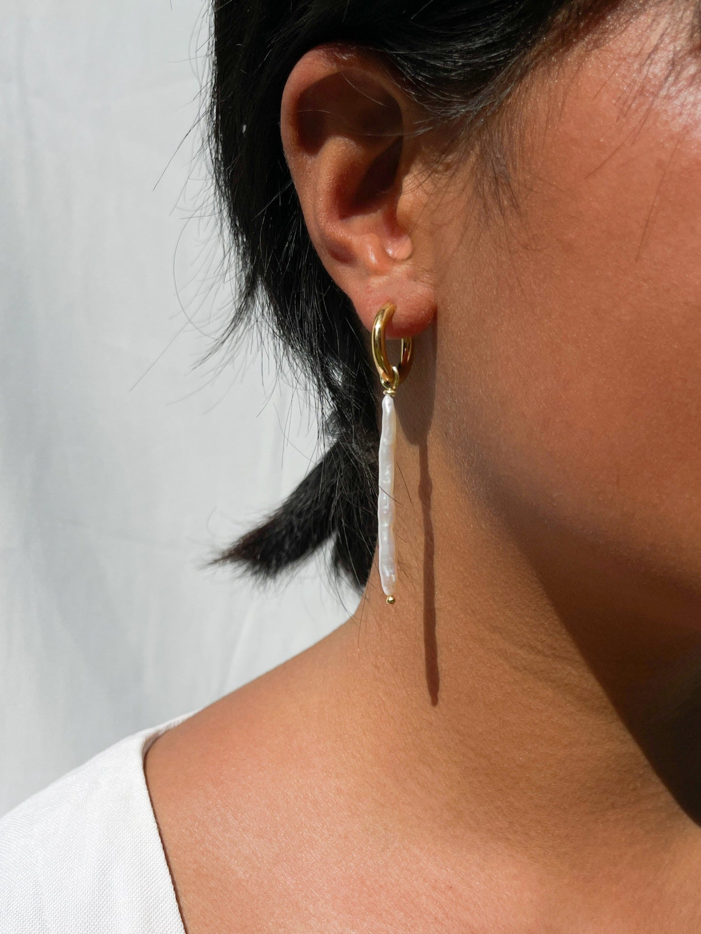 Biwa Pearl Gold Hoops. Chunky 18 karat Gold filled hoops, suspends both elongated Biwa, and round, natural AAA quality freshwater pearls, in a minimal asymmetrical design. Designed and made by nāmaka