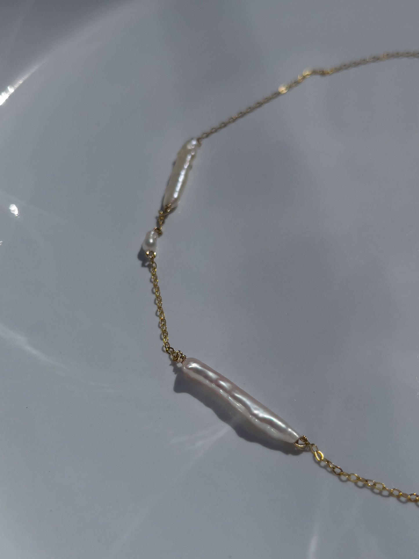 Biwa pearl gold necklace. This ultra fine 14 karat Gold filled with sterling silver flat cable chain suspends gorgeous Biwa elongated freshwater pearls and freshwater seed pearls. Designed and made by nāmaka.